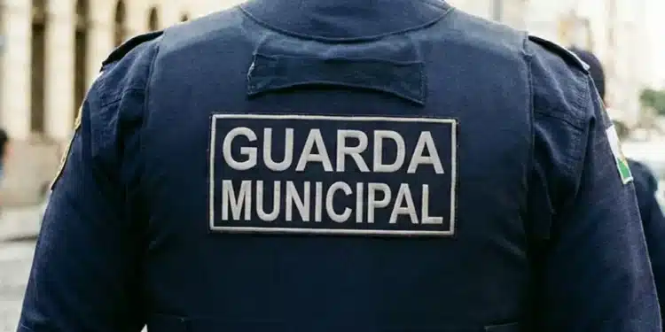 Uniforme de um Guarda Municipal com o texto 'GUARDA MUNICIPAL' visível na parte de trás da camisa, enquanto ele patrulha a cidade, representado a seleção da Prefeitura para o cargo de Guarda Municipal.