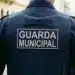Uniforme de um Guarda Municipal com o texto 'GUARDA MUNICIPAL' visível na parte de trás da camisa, enquanto ele patrulha a cidade, representado a seleção da Prefeitura para o cargo de Guarda Municipal.