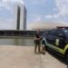 Policial Legislativa Federal ao lado de viatura e cão farejador em frente ao Congresso Nacional em Brasília