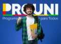 Jovem sorridente com mochila, pastas e livros, em frente ao logo do Prouni.