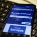 Tela de smartphone exibindo site da Receita Federal, apoiada em teclado.