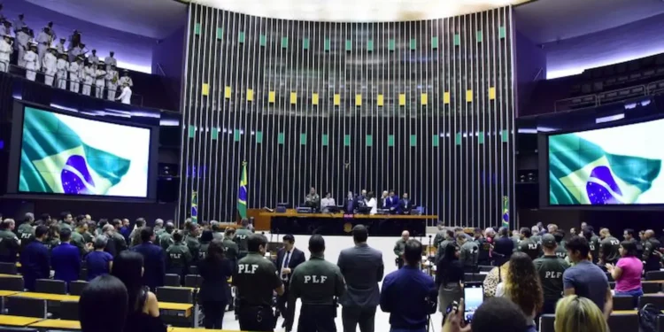 Sessão na Câmara dos Deputados com policial em destaque, em ambiente formal e institucional.