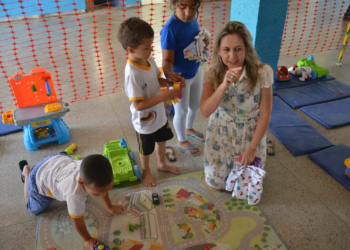 Professora interagindo com crianças pequenas durante atividade lúdica em creche