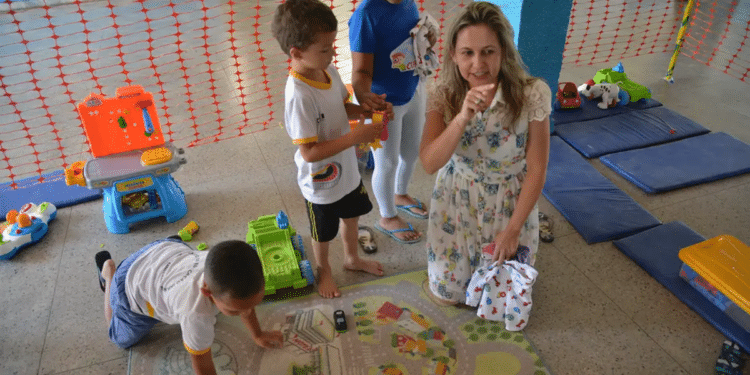 Professora interagindo com crianças pequenas durante atividade lúdica em creche