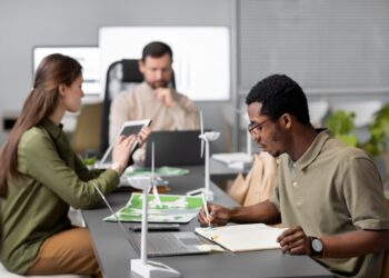 Equipe de profissionais em escritório analisando projetos de energia eólica com maquetes de turbinas