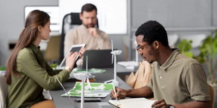 Equipe de profissionais em escritório analisando projetos de energia eólica com maquetes de turbinas