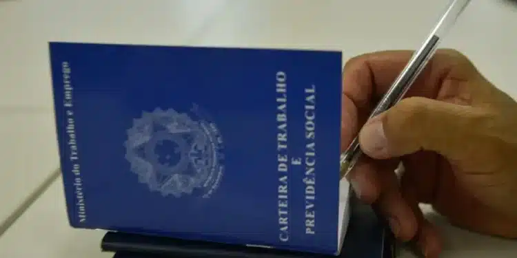 Carteira de Trabalho e Previdência Social sendo preenchida com caneta, representando o processo de solicitação do Seguro-Desemprego.