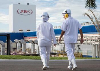 Funcionários da JBS caminhando em frente à unidade industrial da empresa