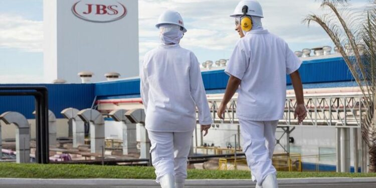 Funcionários da JBS caminhando em frente à unidade industrial da empresa