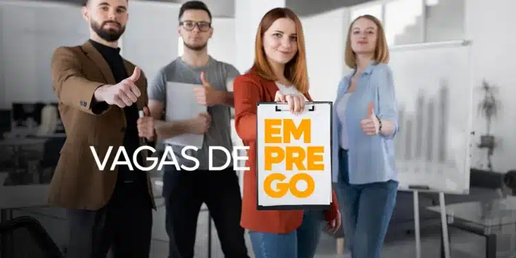 Grupo de quatro jovens profissionais em escritório mostrando sinal de positivo e placa com texto vagas de emprego