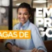 Jovem mulher sorridente sentada à mesa no ambiente de trabalho, com texto "Vagas de emprego".