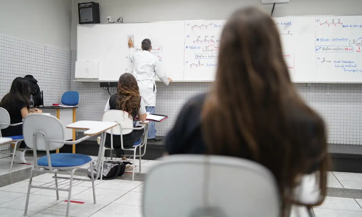 Aula presencial em sala de aula: ensino moderno em 2026 Professor escrevendo quadro branco, alunos atentos em carteiras na sala de aula, ensino em 2026