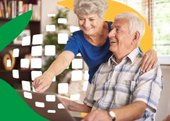 Homem e mulher idosos sorrindo usando laptop com gráficos digitais em casa