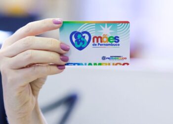 Cartão do programa Mães de Pernambuco sendo segurado, com o logo e a identificação do programa.
