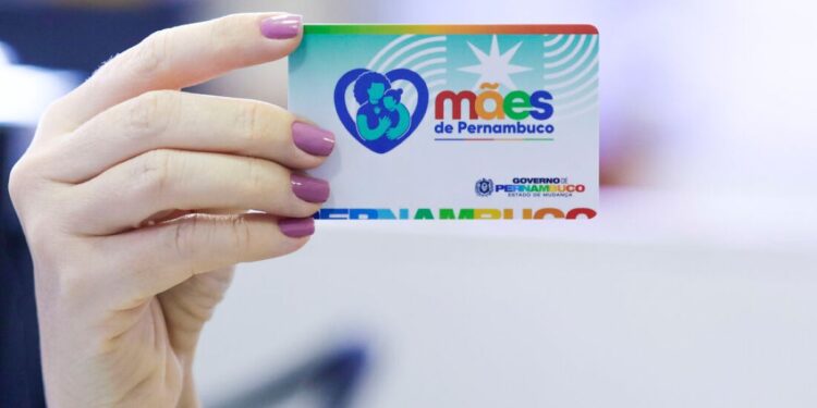Cartão do programa Mães de Pernambuco sendo segurado, com o logo e a identificação do programa.