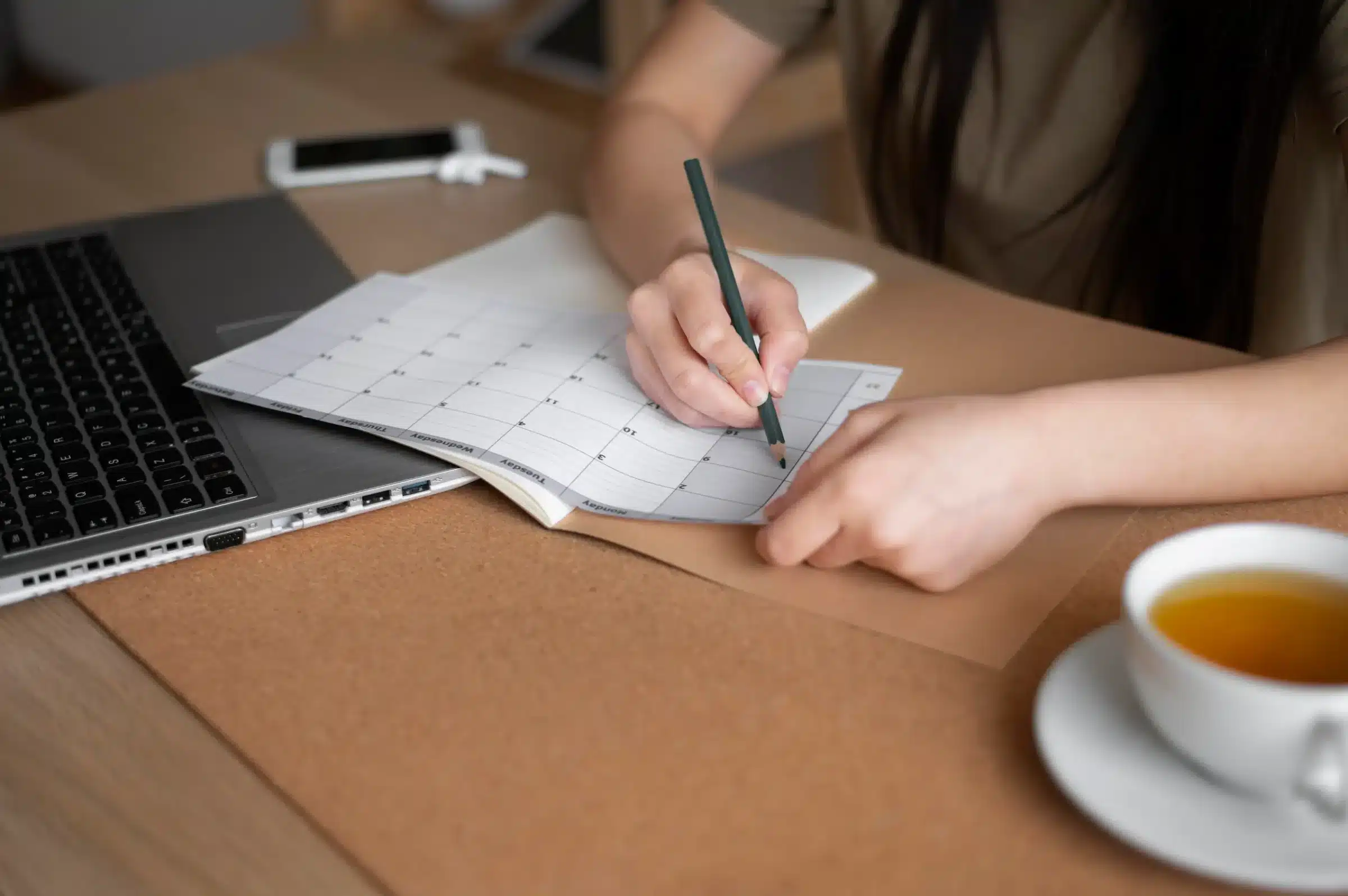 Feriados escolares Imagem ilustrativa de uma pessoa organizando um calendário de estudos no computador, refletindo sobre o que fazer nos dias sem aula.
