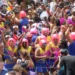 Participantes do Carnaval de 2026 se divertem em um bloco de rua com fantasias coloridas e perucas rosas, celebrando a folia com muito entusiasmo, representando o Carnaval em 2026.