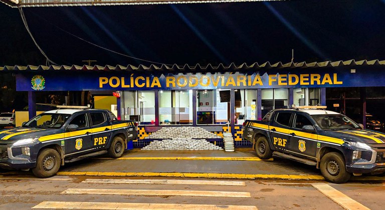 Base da Polícia Rodoviária Federal com viaturas oficiais Viaturas da Polícia Rodoviária Federal estacionadas em frente à base noturna com letreiro iluminado