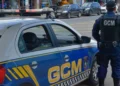 Imagem de um guarda municipal em patrulhamento ao lado de um veículo da Guarda Municipal com a inscrição 'GCM' visível.