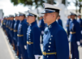 Grupo de cadetes em uniforme azul marinho alinhados durante cerimônia ao ar livre.