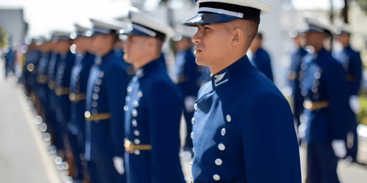 Grupo de cadetes em uniforme azul marinho alinhados durante cerimônia ao ar livre.