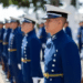 Grupo de cadetes em uniforme azul marinho alinhados durante cerimônia ao ar livre.