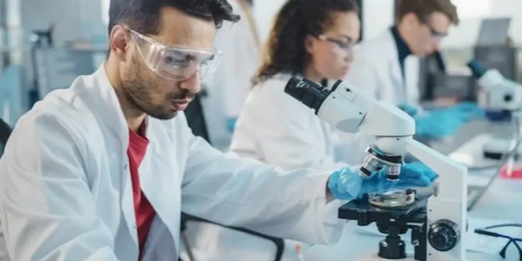 Profissional de laboratório da Fiocruz realizando análise com microscópio, representando a pesquisa e fortalecimento do SUS com novos aprovados no concurso.