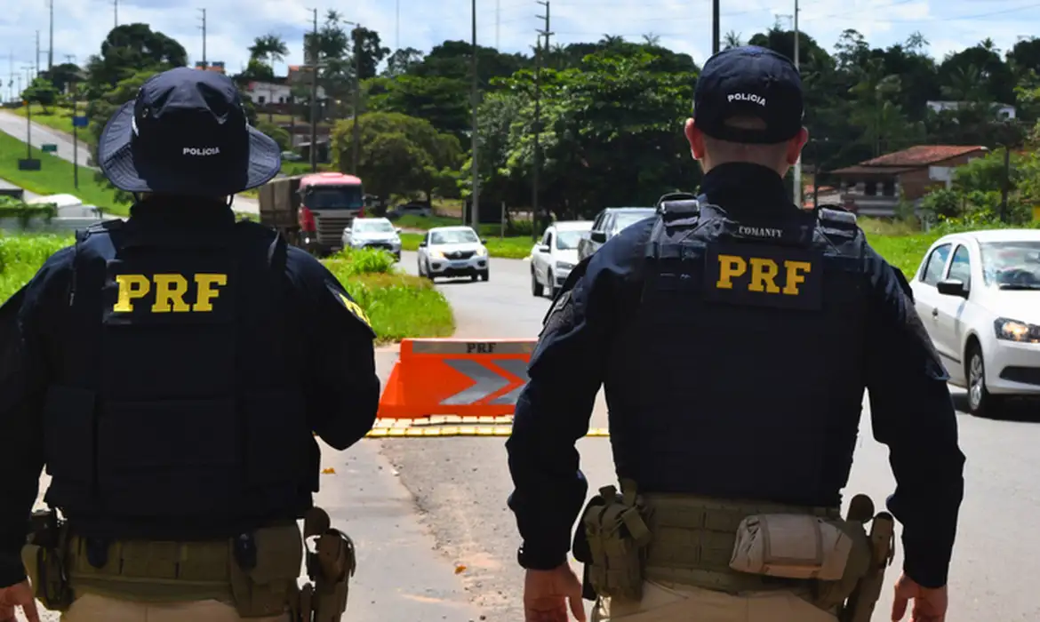 Concurso PRF 2026 Dois agentes da Polícia Rodoviária Federal em fiscalização com veículos na estrada