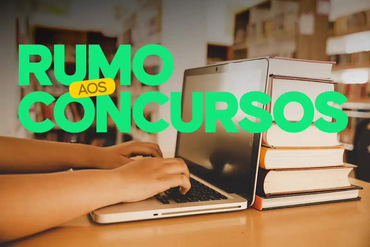 Concursos 2026 Pessoa digitando em laptop ao lado de pilha de livros, representando preparação para concursos