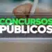 Mão escrevendo em folha de prova com caneta branca e texto Concursos Públicos