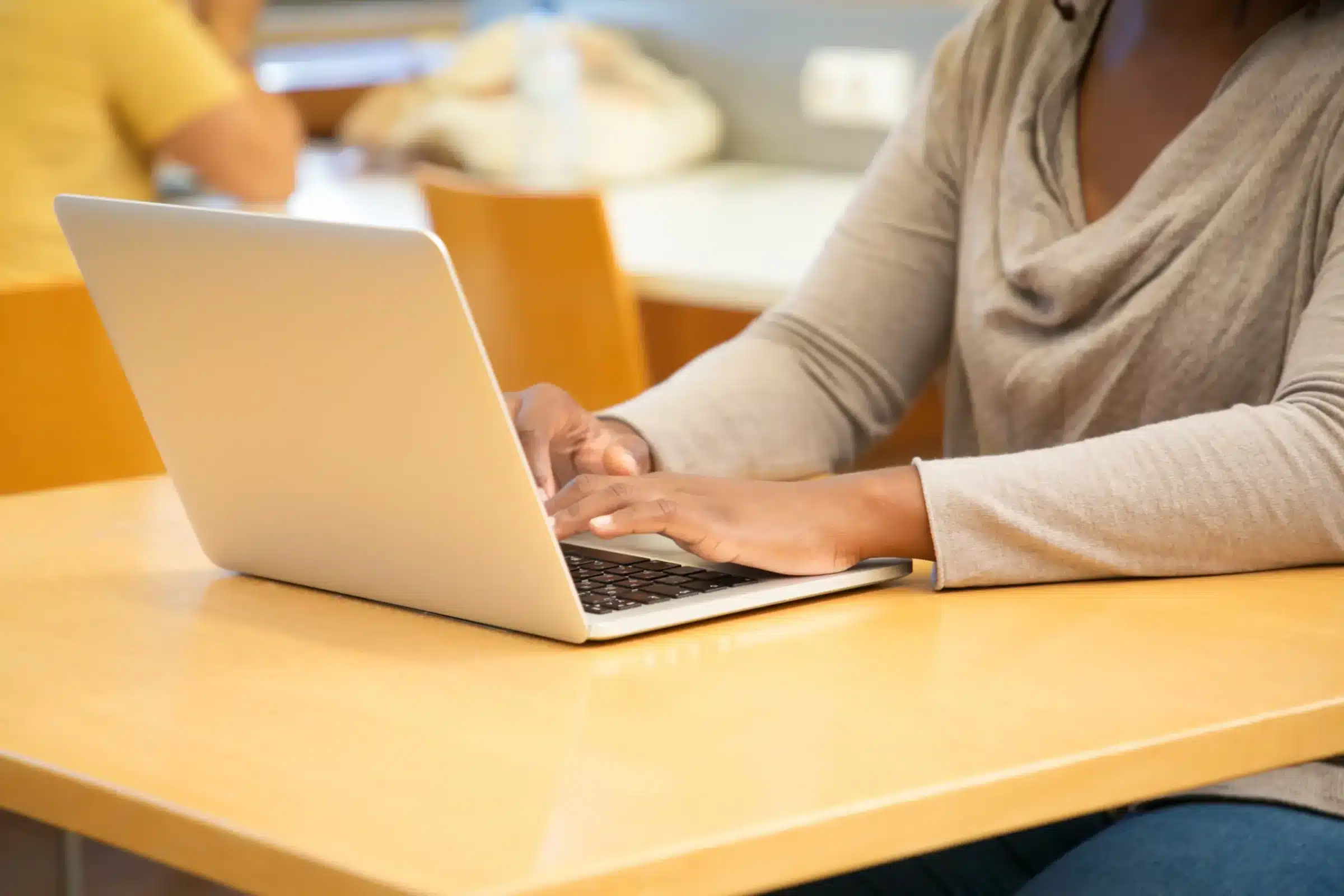 Últimas horas para garantir sua inscrição nos concursos públicos Pessoa digitando no laptop em uma mesa, representando a ação de se inscrever em um concurso público.