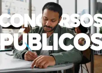 Imagem de uma pessoa escrevendo em um caderno, com foco em concursos públicos durante um ano eleitoral, em um ambiente de escritório.