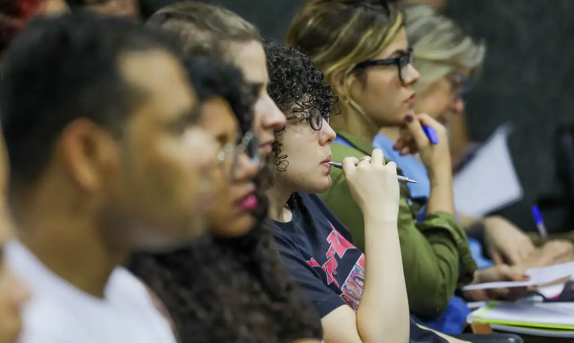 Curso de formação CNU 1 Grupo de estudantes concentrados em sala de aula, anotando e ouvindo com atenção