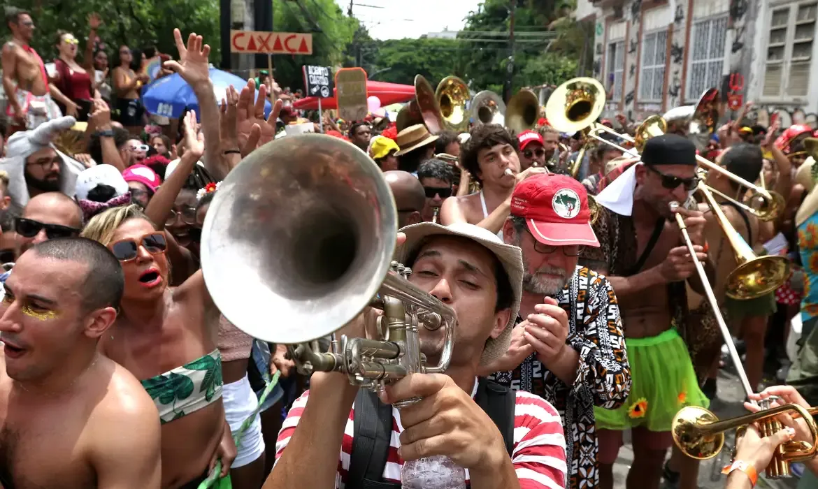 Início do Carnaval em 2026 Festa de Carnaval nas ruas do Brasil, com pessoas se divertindo e tocando instrumentos musicais em bloco de rua.