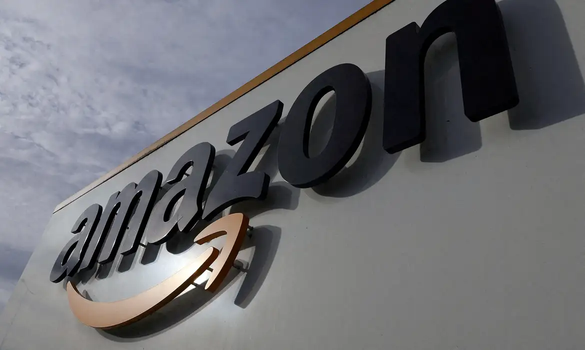Fachada da Amazon reforça identidade de inovação global Logotipo da Amazon em destaque na fachada de um edifício moderno, ilustrando mudanças e cortes de vagas na empresa de tecnologia
