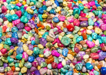 Pedrinhas coloridas com a semente de romã oculta entre elas, em um desafio visual.