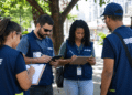 Equipe do IBGE com pranchetas e tablet durante atividade de campo em área urbana.