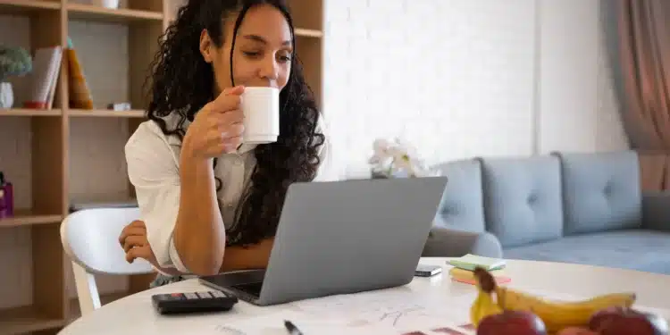 Profissional de home office trabalhando com computador e café, simbolizando as profissões com maiores oportunidades no mercado de trabalho em 2026.