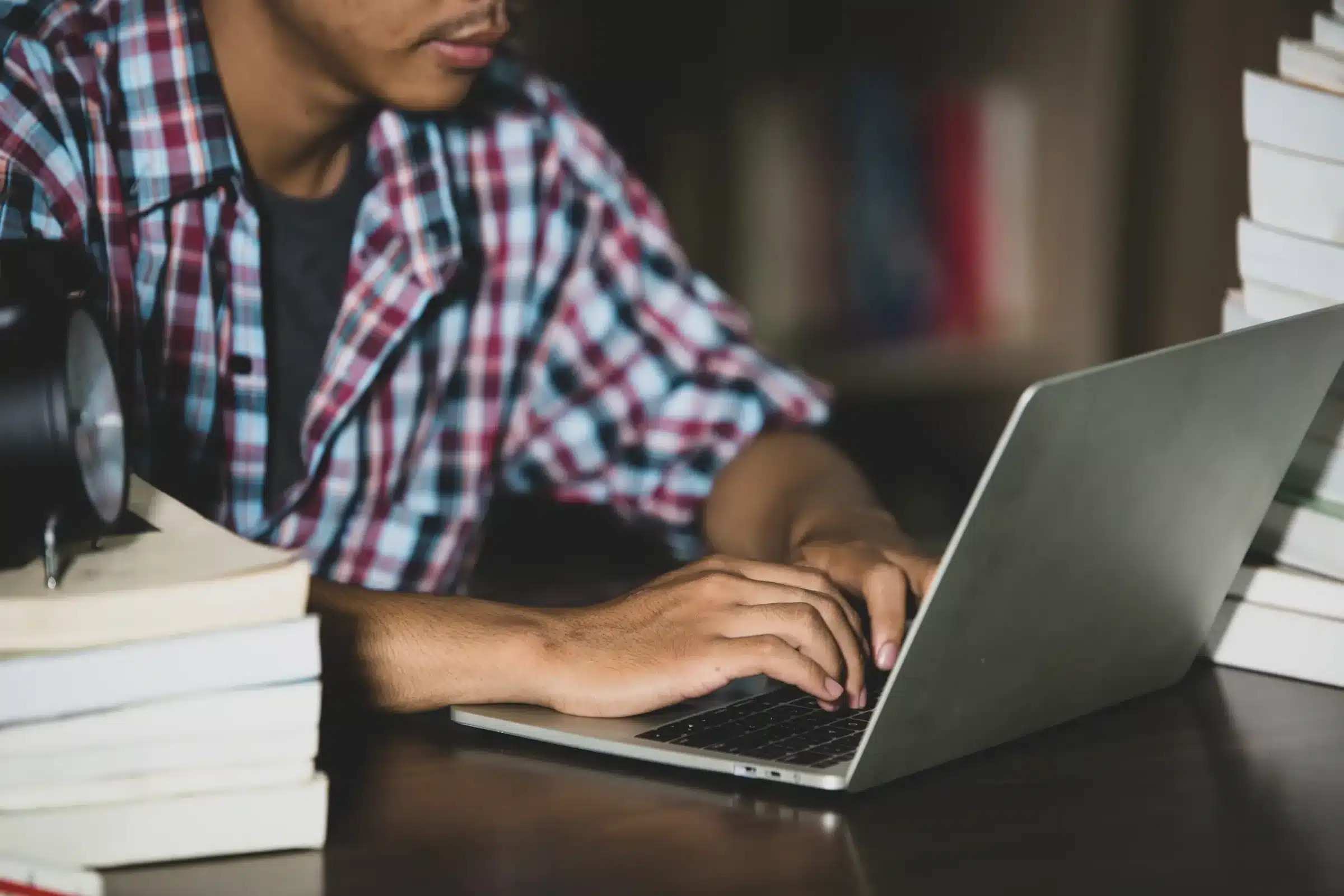 Inscrições Abertas para Concursos Públicos - Participe Hoje! Pessoa digitando no laptop em meio a livros, representando a preparação para concursos públicos.