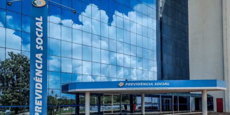 Fachada moderna da sede da Previdência Social com logotipo em destaque e céu refletido no vidro