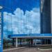 Fachada moderna da sede da Previdência Social com logotipo em destaque e céu refletido no vidro