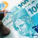 Notas de 100 reais representando o 13º salário do INSS, com isenção de Imposto de Renda em 2026.