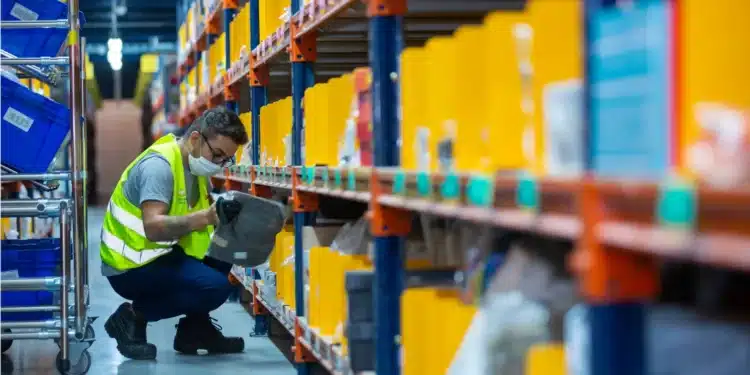 Funcionário em armazém do Mercado Livre, manuseando embalagem em prateleira de estoque, em um ambiente de logística e tecnologia.