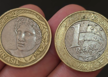 Duas moedas de 1 real de 1998 lado a lado; a da esquerda mostra o anverso com a efígie da República e a da direita exibe o valor de face, o ano 1998 e o núcleo prateado.