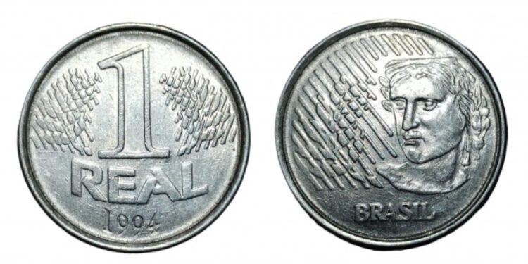 Visão detalhada das duas faces da primeira moeda de 1 real do Brasil, lançada em 1994. À esquerda, o reverso com o número 1 sobre ramos de louro; à direita, o anverso exibindo a efígie da República e a palavra "Brasil" sobre um fundo branco.