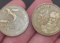 Duas moedas de 25 centavos de 1999 sendo seguradas, mostrando as faces anverso (busto de Deodoro) e reverso (valor "25 centavos").