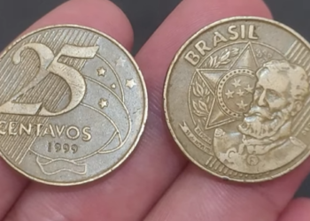 Duas moedas de 25 centavos de 1999 sendo seguradas, mostrando as faces anverso (busto de Deodoro) e reverso (valor "25 centavos").