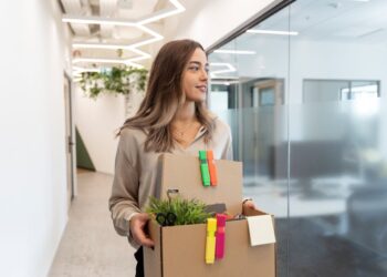 Mulher segurando caixa de mudanças no escritório, simbolizando a transição de carreira.