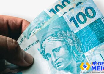 Notas de R$100 do Brasil sendo seguradas, representando o valor do Pix a ser recebido em fevereiro pelo Pé-de-Meia.