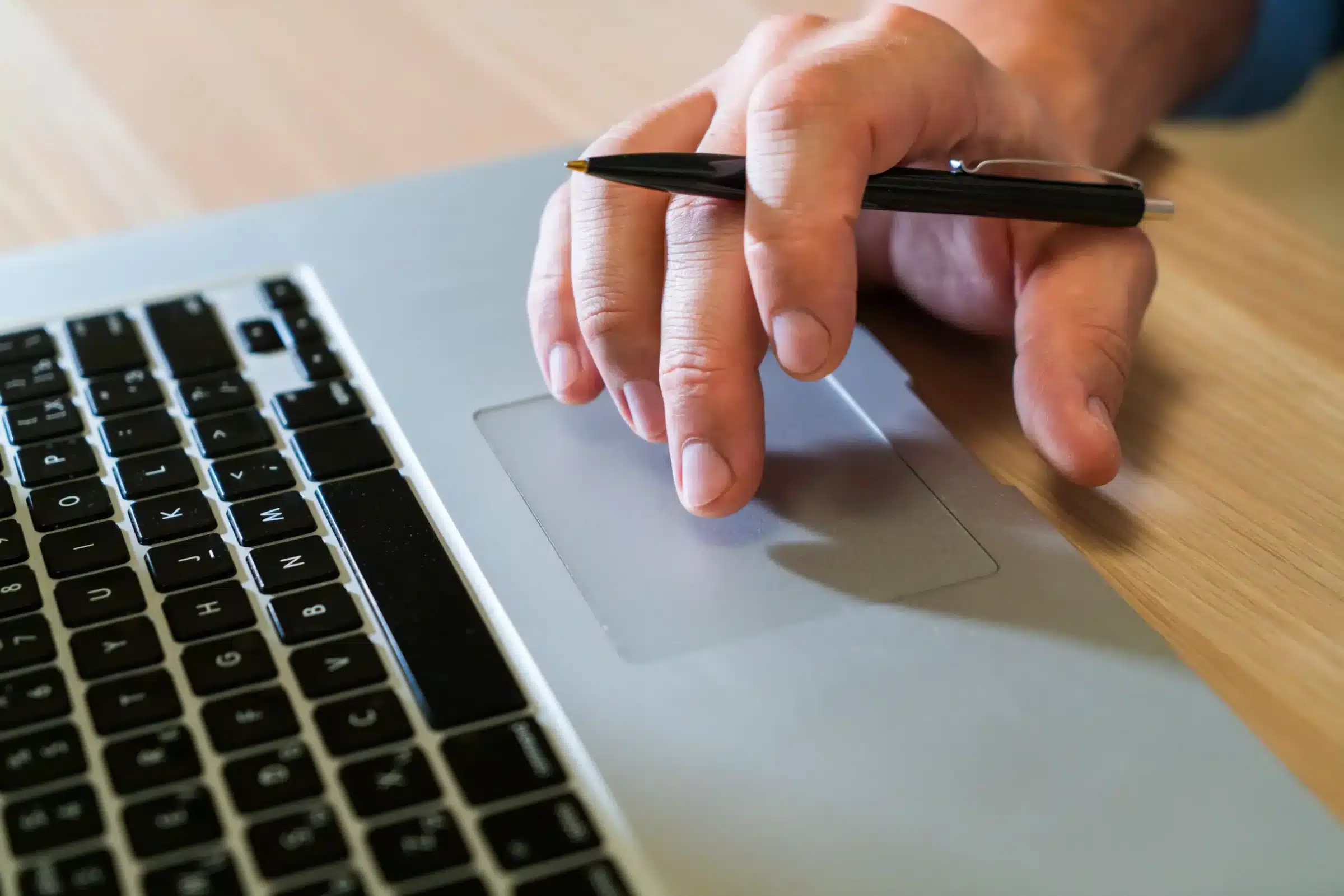 Requisitos para participar do processo seletivo da Prefeitura de Ituiutaba Pessoa utilizando um laptop com uma caneta na mão, representando a inscrição no processo seletivo da Prefeitura de Ituiutaba.